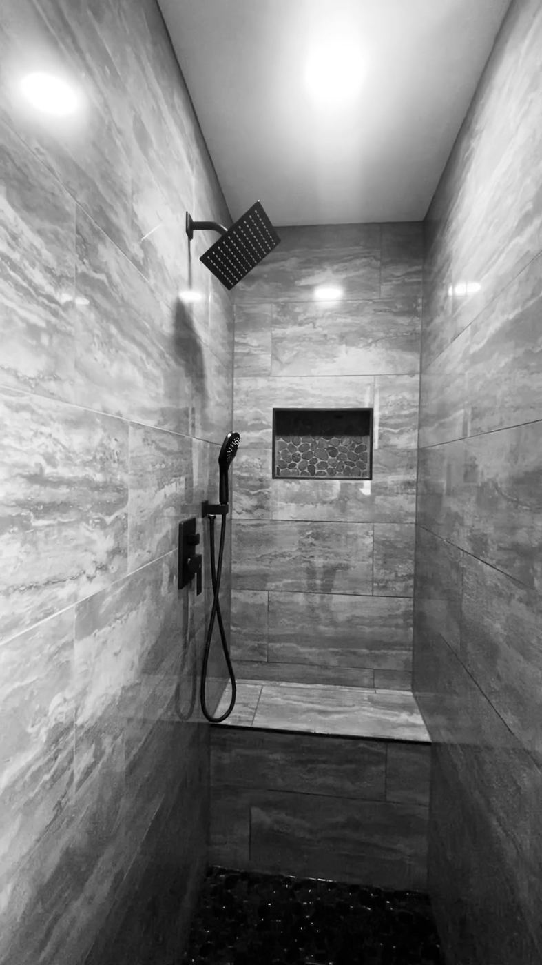 Walk-in tile shower with a rain head and pebble floor