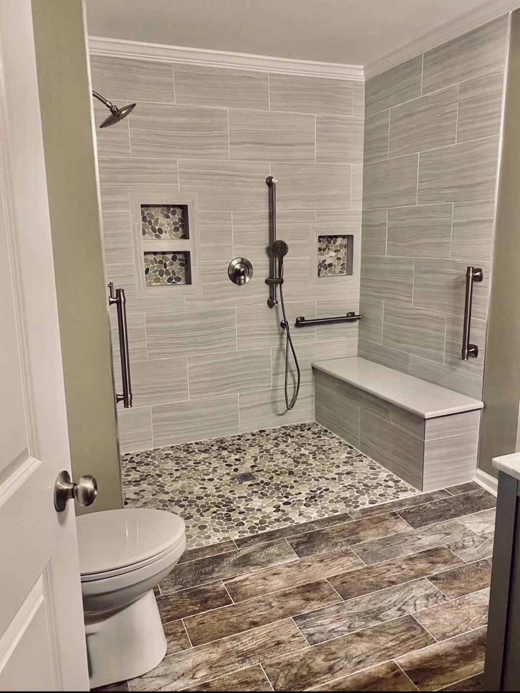 Roll-in tile shower with a bench, grab bars and lit niches